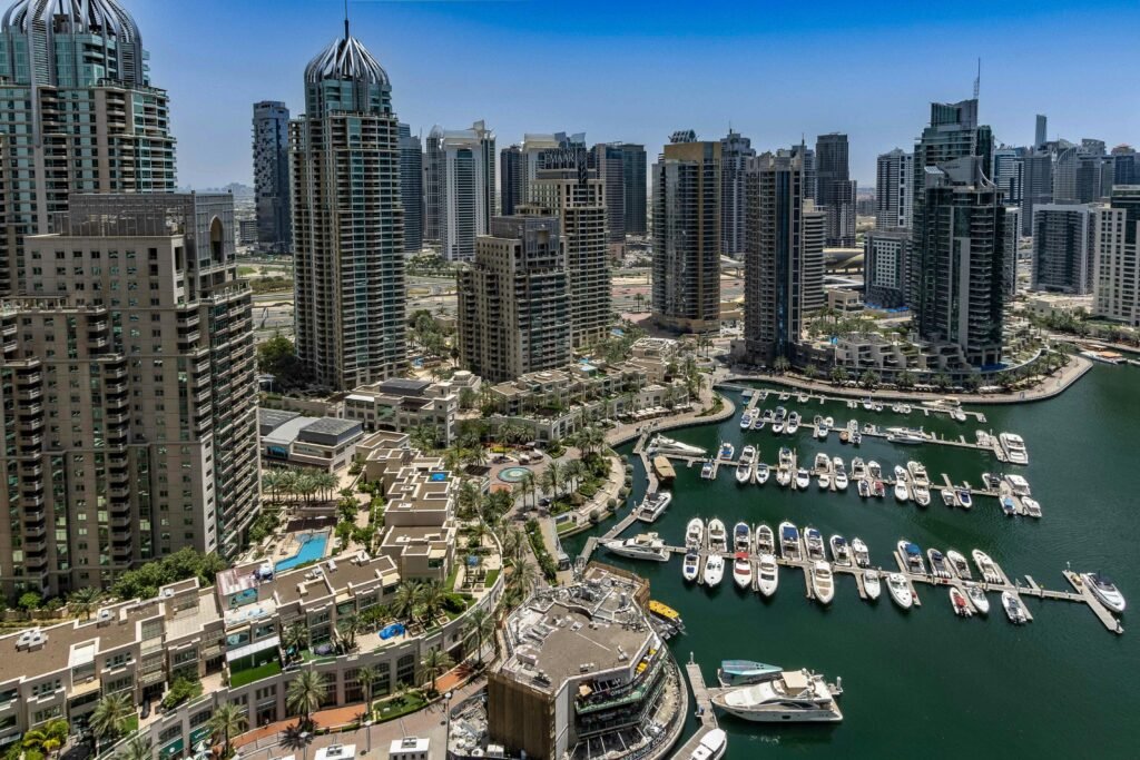 Aerial view of Dubai Marina with modern skyscrapers and luxurious yachts docked, showcasing urban architecture.